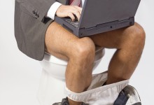 man with laptop sitting on the toilet