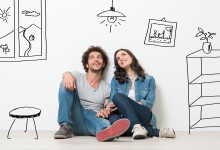 Portrait Of Happy Young Couple Sitting On Floor Looking Up While